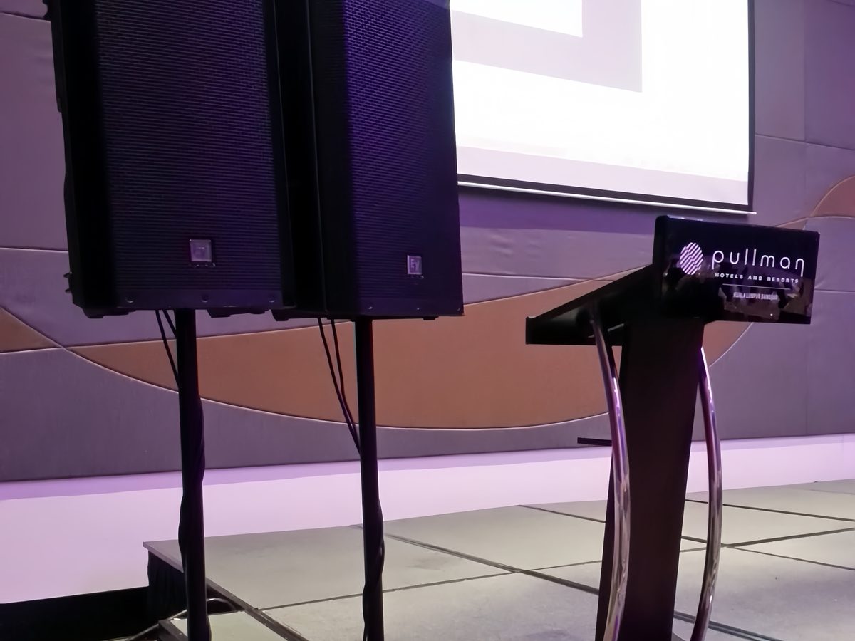 Projection screen, podium and PA speakers set on a hotel ballroom stage