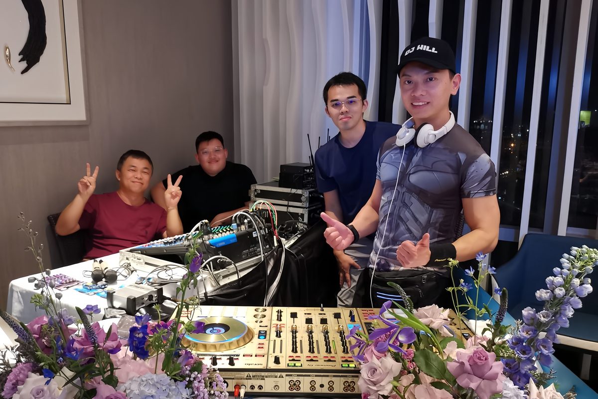 Four Event Foo crew at a gold DJ console dressed with flowers