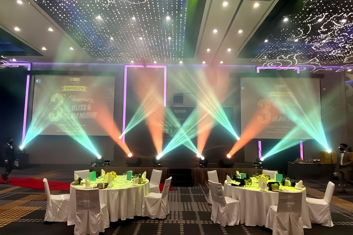 Teal and amber beams across an anniversary dinner stage