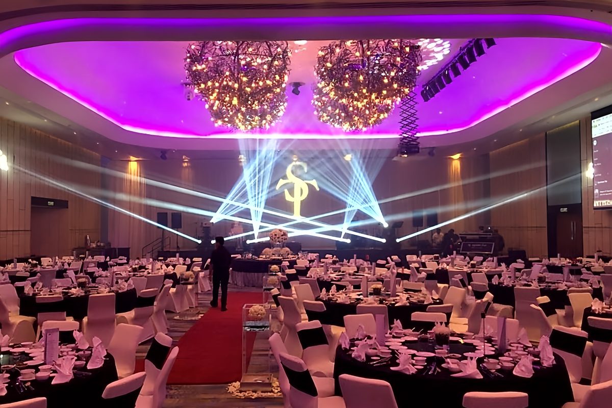 Laser fans and purple cove lighting over an awards dinner