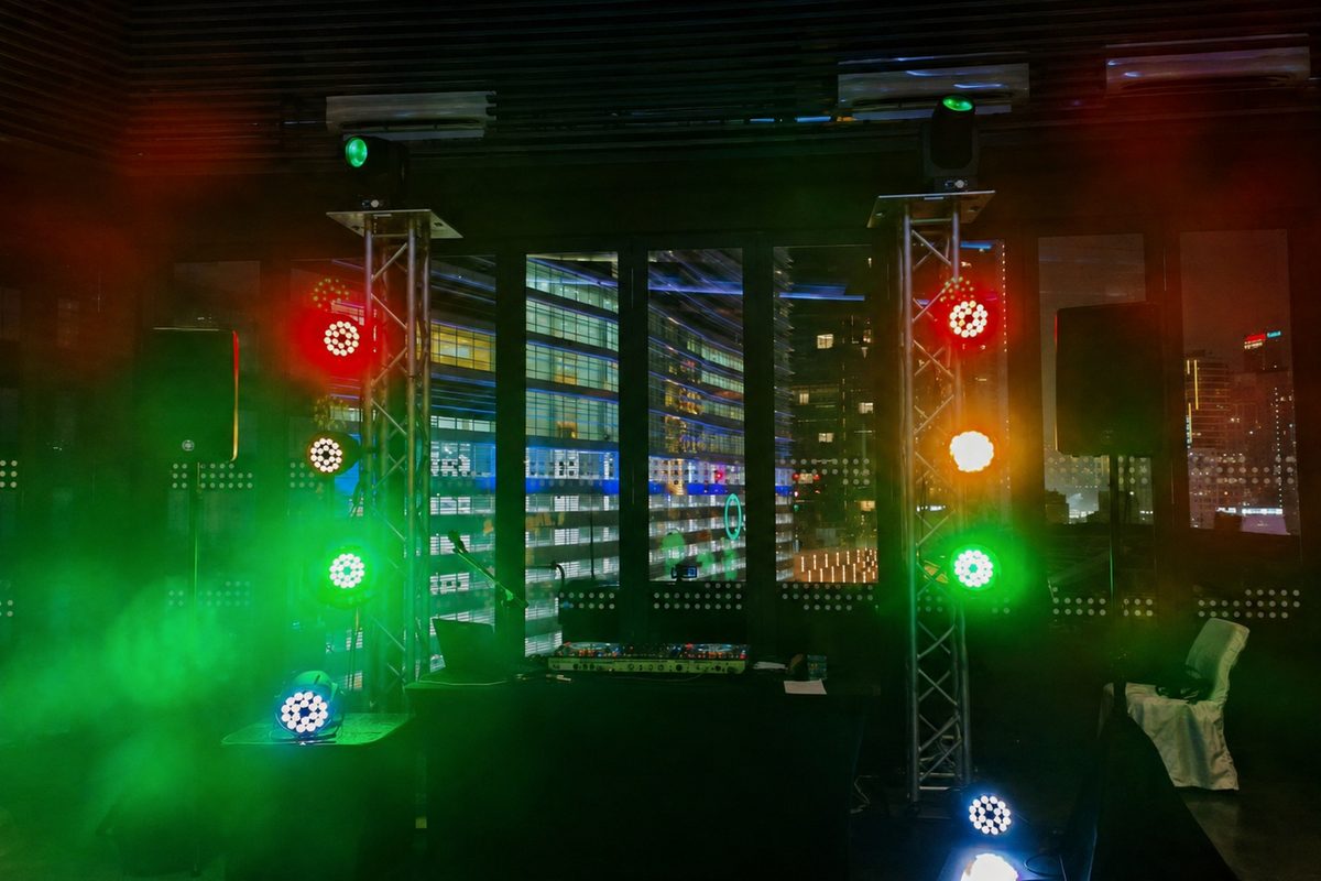 Par fixtures on truss towers in haze, city skyline behind