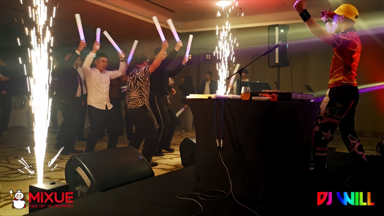 Guests cheering with glow sticks as cold sparks fire beside the DJ booth at the MIXUE 2nd Anniversary Annual Dinner