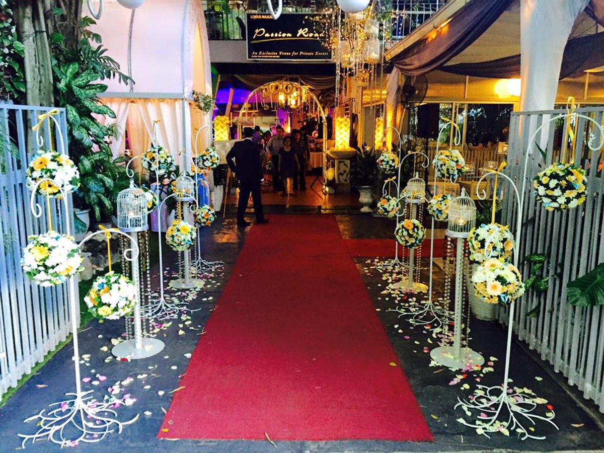 Red carpet aisle lined with floral stands